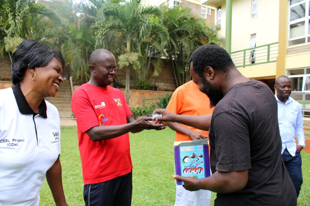 The Head, Department of Humanities and Language Education, Dr. Muhammad Kiggundu Musoke (2nd L) receives one of the activity items from Dr. Oscar Mugula (R).