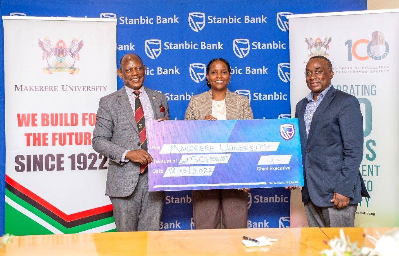 The Vice Chancellor, Prof. Barnabas Nawangwe (L) and CEO & Head Mak@100 Secretariat, Mr. Awel Uwihanganye (R) receive the dummy cheque of UGX 150 Million from Ms. Anne Juuko, CEO, Stanbic Bank Uganda on 18th May 2022.