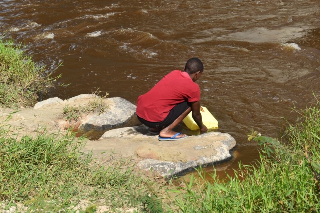 A student drawing water from River Rwizi