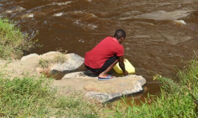 A student drawing water from River Rwizi.