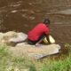 A student drawing water from River Rwizi.