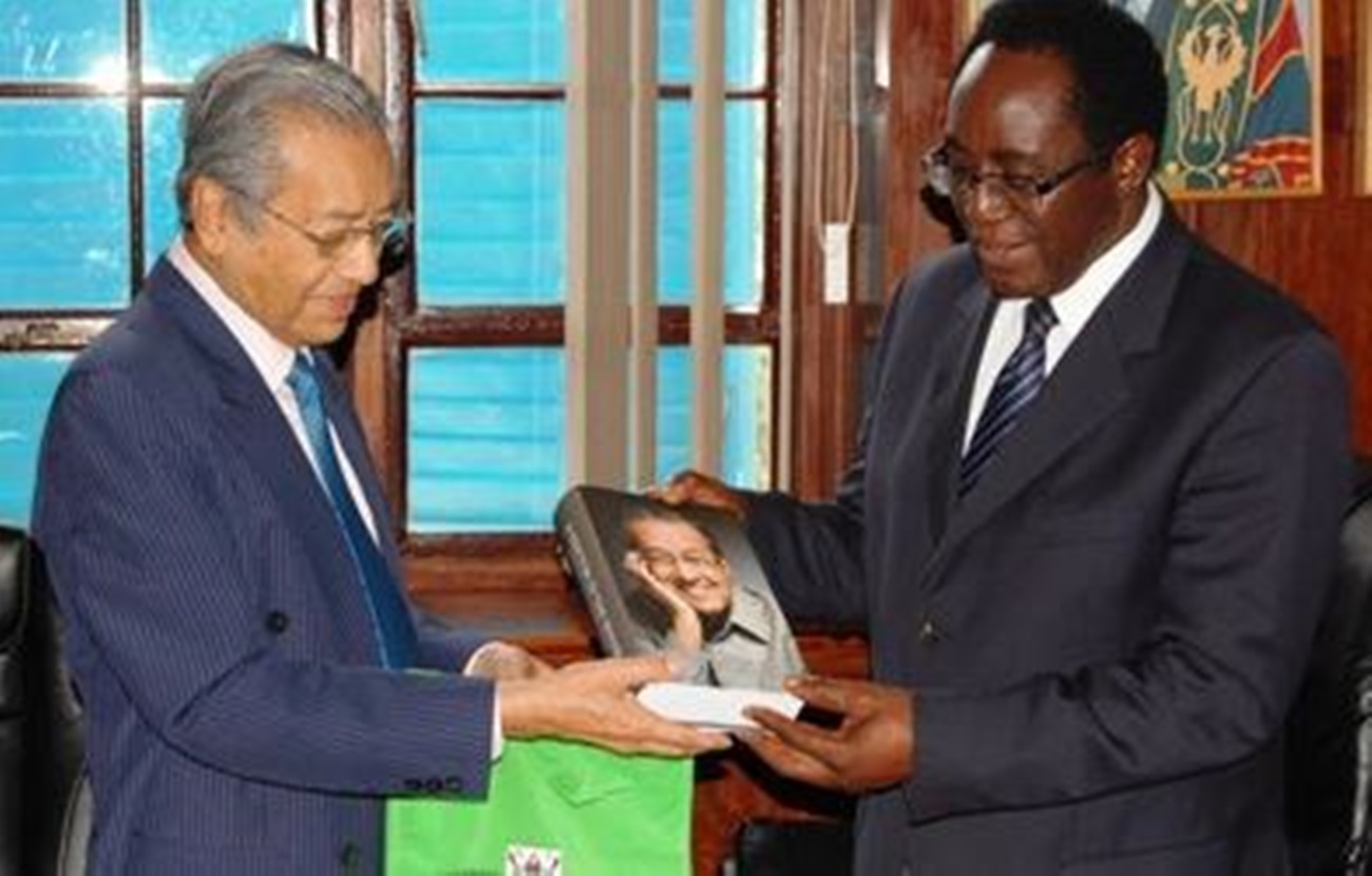 The Former Prime Minister of Malaysia, H.E. Tun Dr. Mahathir Mohamad (L) presents a copy of his book titled "A DOCTOR IN THE HOUSE: The Memoirs of Tun Dr. Mahathir Mohamad." to the Vice Chancellor, Professor John Ddumba-Ssentamu on 30th October 2012 in the Council Room, Makerere University.