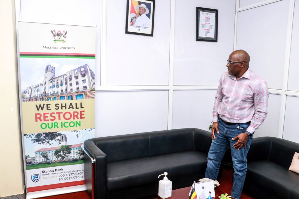 Dr. Sambisa carefully looks at a photo of the remains of the iconic Makerere University Main Building.