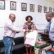 The Acting Deputy Vice Chancellor Finance & Administration, Prof. Tonny J. Oyana (R) presents an assortment of Makerere University souvenirs to BMGF's Dr. William Sambisa (L) during the courtesy call on 4th July 2022, Frank Kalimuzo Central Teaching Facility. Centre is the Dean MakSPH, Prof. Rhoda Wanyenze.