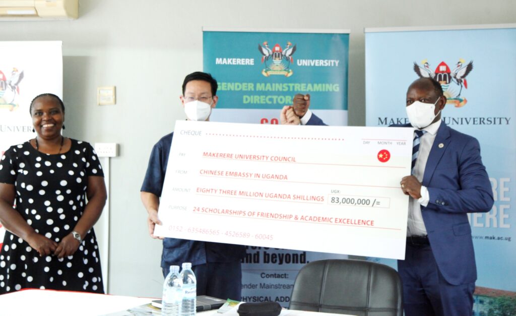 H.E. Zhang Lizhong (C) presents the dummy cheque to Prof. Barnabas Nawangwe (R) as Dr. Euzobia Baine Mugisha (L) witnesses. 