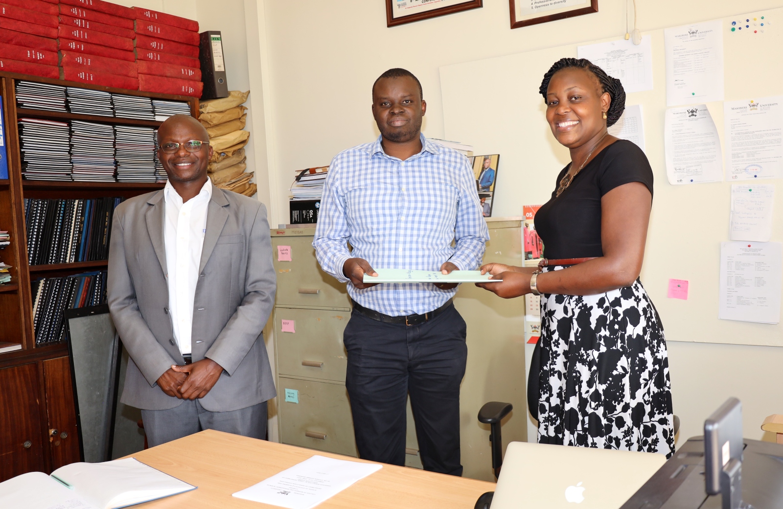 The Dean School of Statistics and Planning (SSP) Dr. James Wokadala (L) witnesses as outgoing Head of the Department of Population Studies, Dr. Stephen Ojiambo Wandera (C) hands over to incoming Head, Dr. Patricia Ndugga on 1st July 2022, CoBAMS, Makerere University.