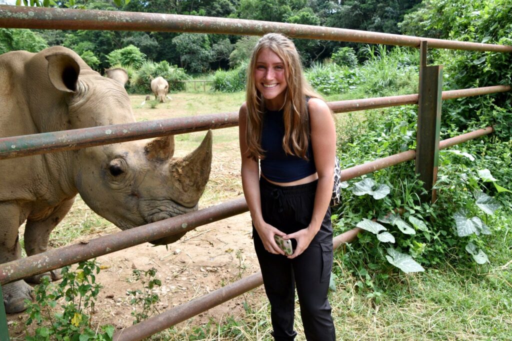 A Mississippi State University Student out in the field of wildlife conservation, just next to a rhino.