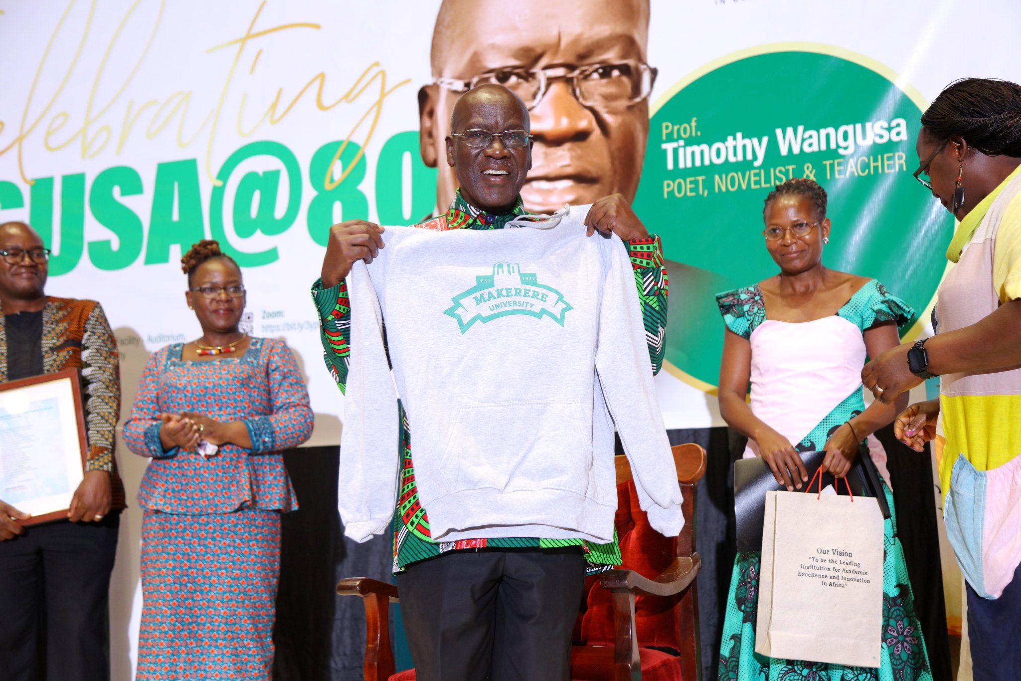 Professor Timothy Wangusa shows off his Makerere Hoodie, one the items in the assortment of souvenirs presented to him during the celebrations on 8th July 2022, Yusuf Lule Central Teaching Facility Auditorium, Makerere University.