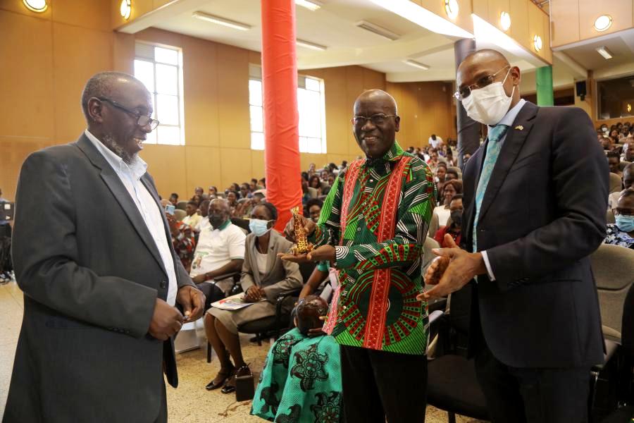 Professor Abasi Kiyimba (L) present a gift to Professor Timothy Wangusa as the DVCAA, Professor Umar Kakumba witnesses.