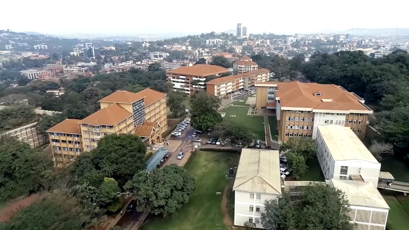 An aerial view of Left to Right: Mitchell Hall, Senate, CoCIS Blocks B and A, Lincoln Flats, Frank Kalimuzo Central Teaching Facility and School of Social Sciences (white) Buildings, Makerere University, with Kampala City in the background, October 2018. Uganda.