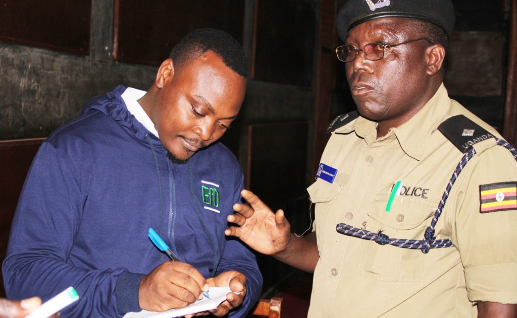 EfD-Mak Data Manager Fred Kasalirwe interacts with the police commander after the meeting.