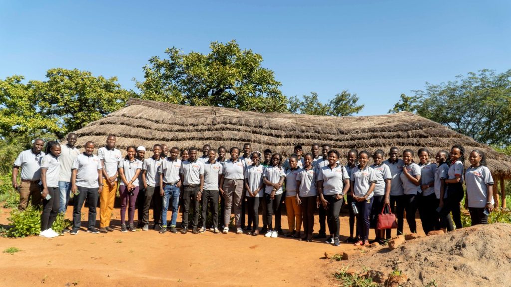Ms. Grace Sennoga (centre) and scholars pose in front of the old structure where children used to study from.