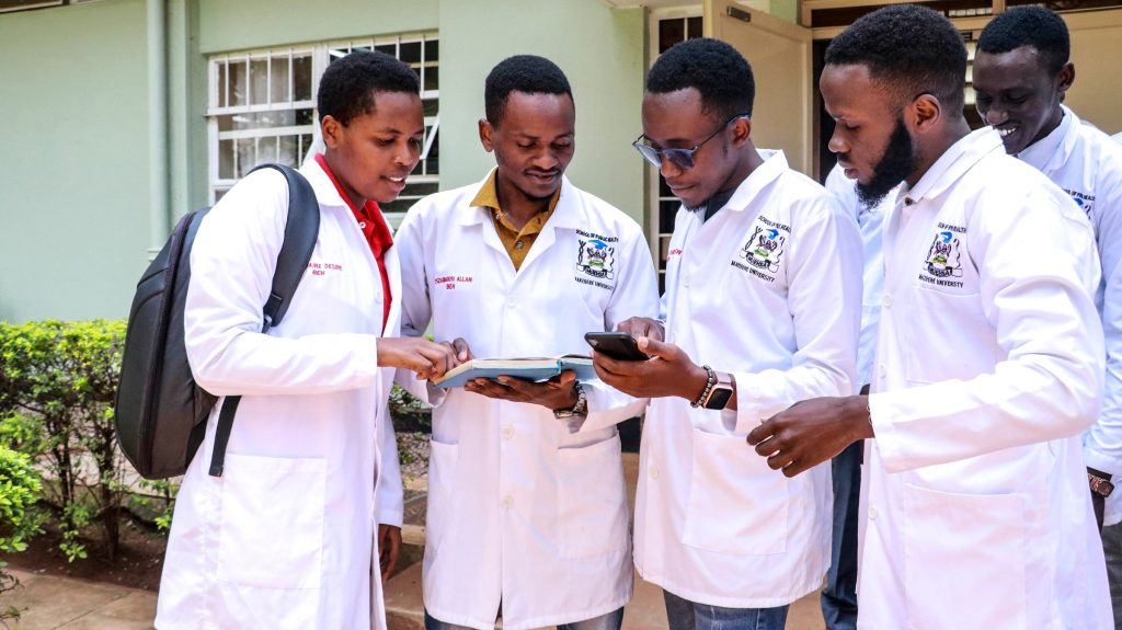 Allan Ssembuusi, (second left) discussing with classmates at Makerere School of Public Health last year. Photo by Davidson Ndyabahika.