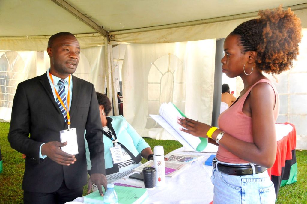 Mr. Dennis Kibuuka (L) has a one-on-one session with a visitor to the Makerere University exhibition space. 