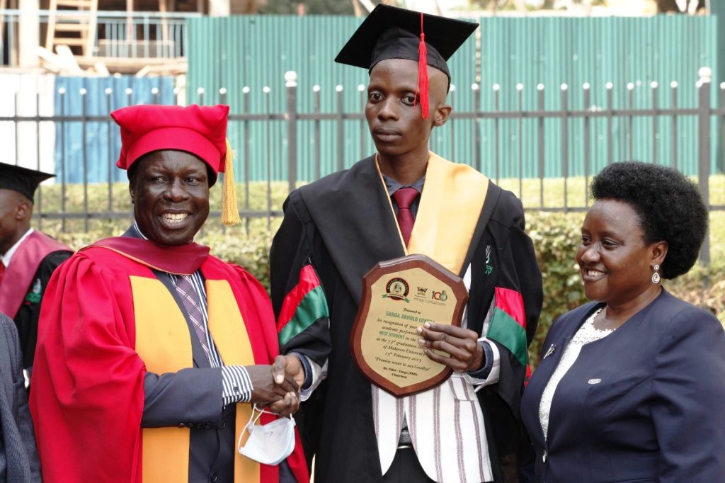 Chair Convocation-Dr. Tanga Odoi (L) and Deputy Chair Convocation-Mrs. Diana Hope Nyago (R) congratulate the Best Overall Sciences Student-Mr. Sanga Arnold Lukoda (C) who attained a CGPA of 4.85 in the Bachelor of Information Systems and Technology to emerge the Best Overall Sciences Student at the 73rd Graduation Ceremony of Makerere University.