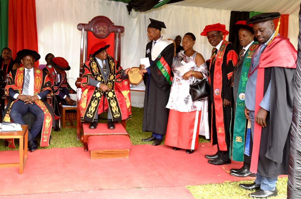 Prof. Ezra Suruma presents the Convocation Plaque to Mr. Owomugisha Jordan (3rd L) and his mother as Prof. Barnabas Nawangwe (L) Prof. Waswa Balunywa (3rd R), Prof. Moses Muhwezi (2nd R) and others witness.