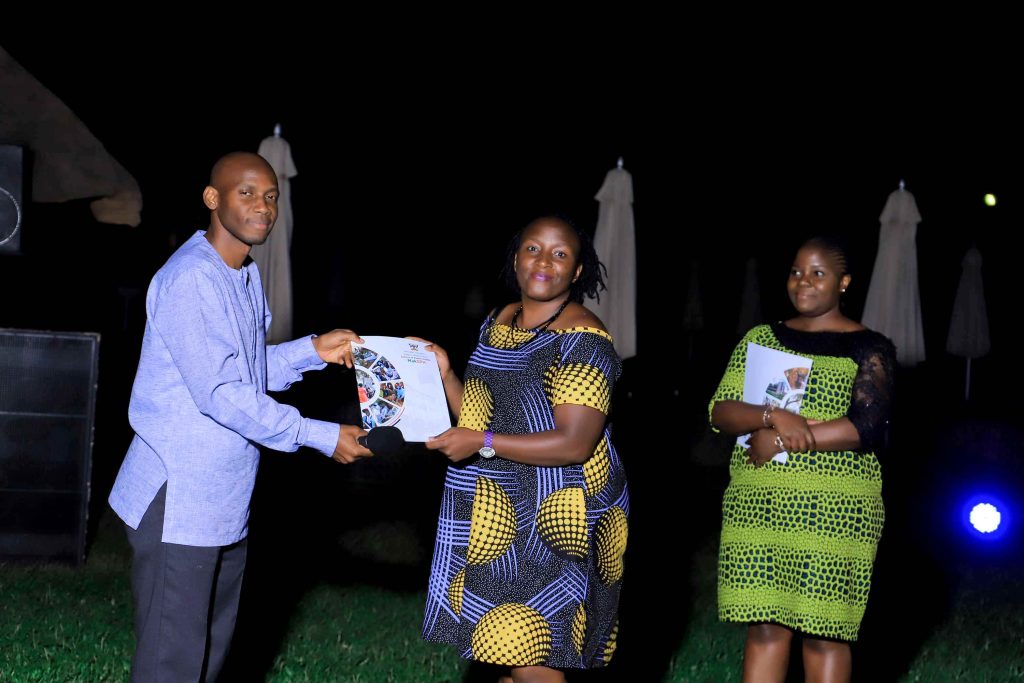 Dr. David Musoke (L) handing over the grant award to Ms. Juliana Namutundu (C).