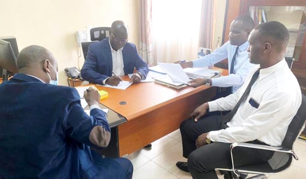 Left to Right: Prof. Andrew Ellias State and Dr. Justus Twesigye sign handover documents witnessed by Mr. Makubuya Godfrey and Mr. Luwuliza Aggrey in the Deans office.