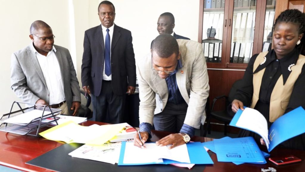 College HR Officer Mr. Godwin Okiror signs the handover documents as witness.