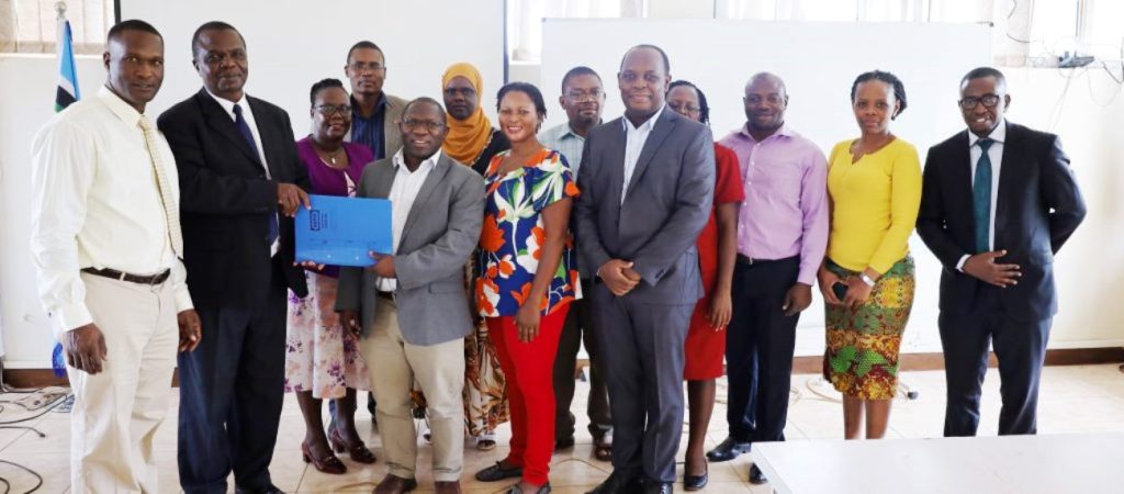 Front Row: Assoc. Prof. Gilbert Mayiga (2nd R) hands over to Dr. Joseph Balikuddembe (3rd R) as College and University staff witness.