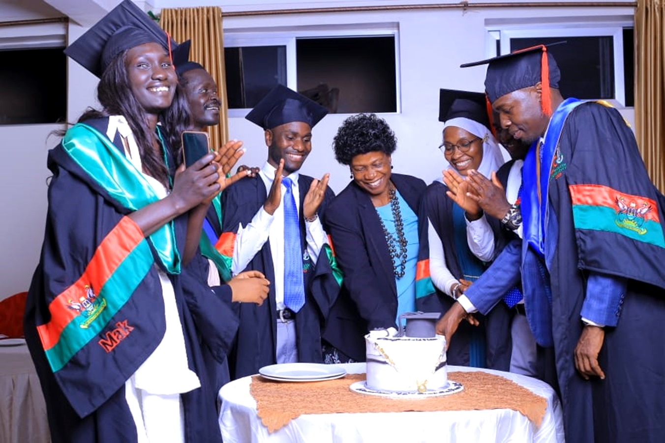 The Head, International Office at Makerere University, Ms. Martha Muwanguzi (Centre) joins a section of international graduates to cut cake during their graduation party on 25th February 2023.