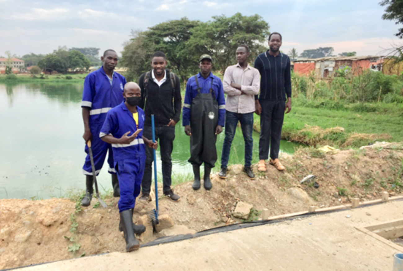 A group photo of sanitation workers dressed in overalls and research assistants at a lagoon in one of the study cities.