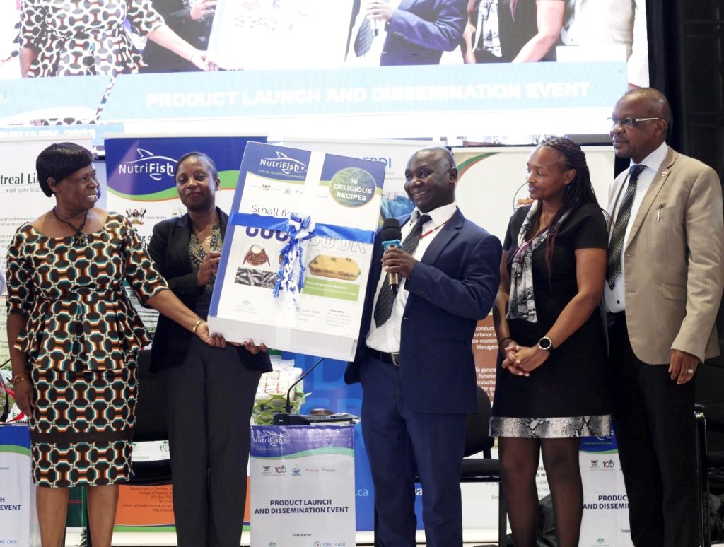 Mr. Tom Mukasa Bukenya (Centre) launching the cookbook developed under the project.