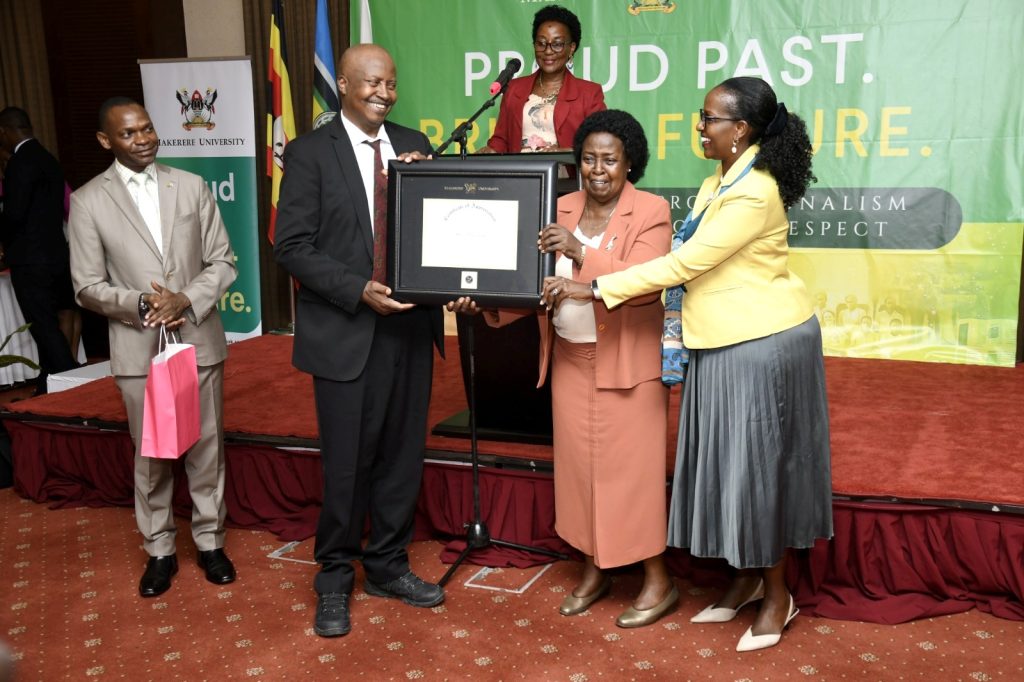 Mrs. Margaret Kakitahi Bikangaga (2nd Right) and Eng. Andrew Bikangaga (2nd Left) receive the Certificate of Recognition on behalf of their late father Canon John Bikangaga from Mrs. Lorna Magara (Right) as Prof. Umar Kakumba (Left) and Prof. Gorettie Nabanoga (Rear) witness. 