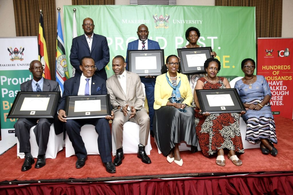 Seated Left to Right: Prof. Livingstone Luboobi, Prof. George Kirya, Prof. Umar Kakumba, Mrs. Lorna Magara, Ms. Phyllis Kalimuzo and Mrs. Betty Mugoya Kajubi. Standing Left to Right: Mr. Daniel Kalimuzo, Mr. Martin Mwanje and Ms. Samalie Kajubi pose with their Certificates of Recognition. 