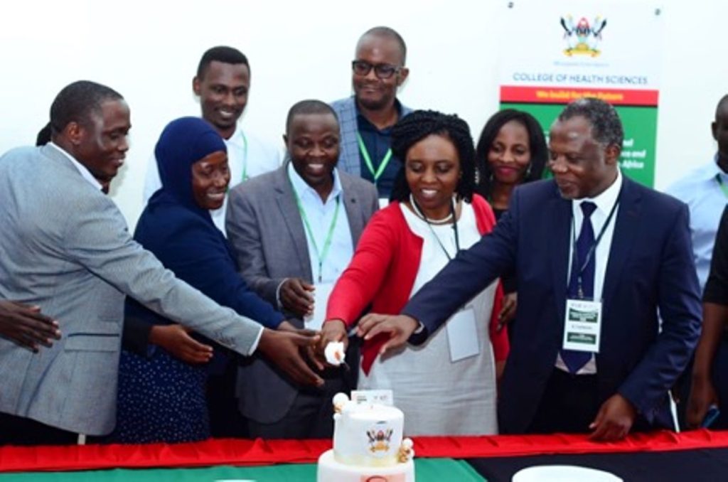 Professor Damalie Nakanjako (2nd right), Dr. Besigye Innocent (3rd right) and Dr. Fred Bukachi (1st right) cutting cake with other key stakeholders at the symposium.