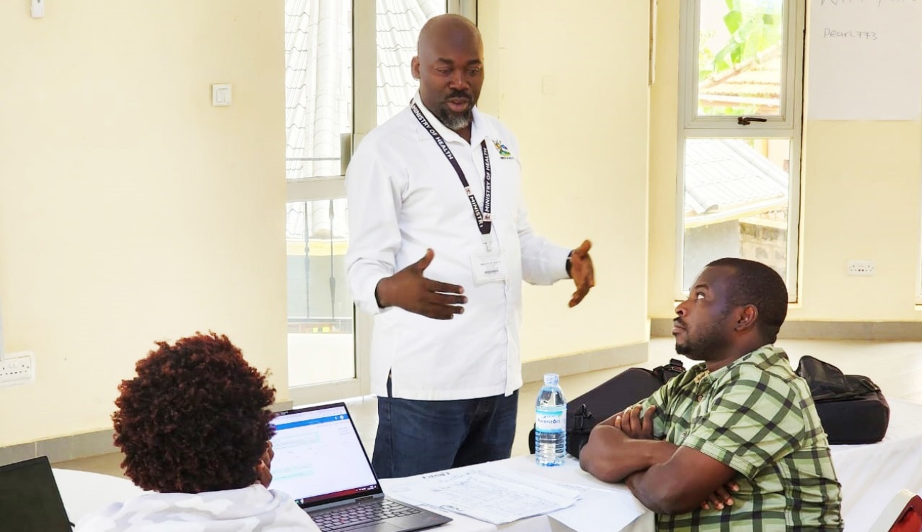 Assistant Commissioner Health Systems for Health Information Management Division, Paul Mbaka (Standing) guides the team on metadata adjustments during the Master Facility List (MFL) and electronic Health Management Information System updates and configuration in March 2023. Photo: METS.