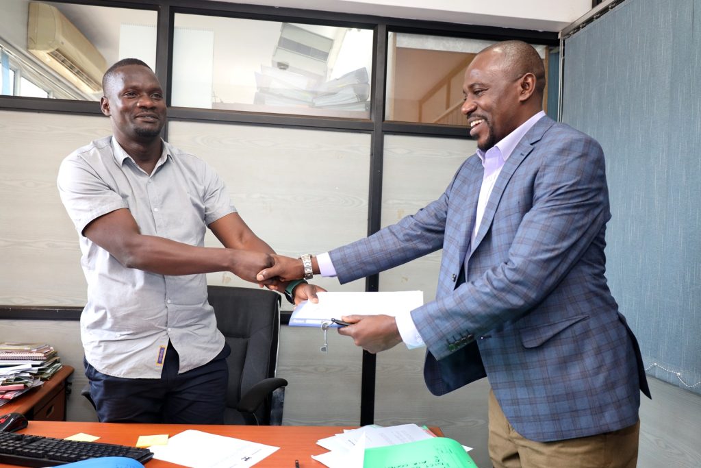 Mr. David Ikomo (Left) and receives the handover report from Mr. Stephen Byarugaba (Right). Block A, College of Computing and Information Sciences (CoCIS), Makerere University, Kampala Uganda, East Africa.