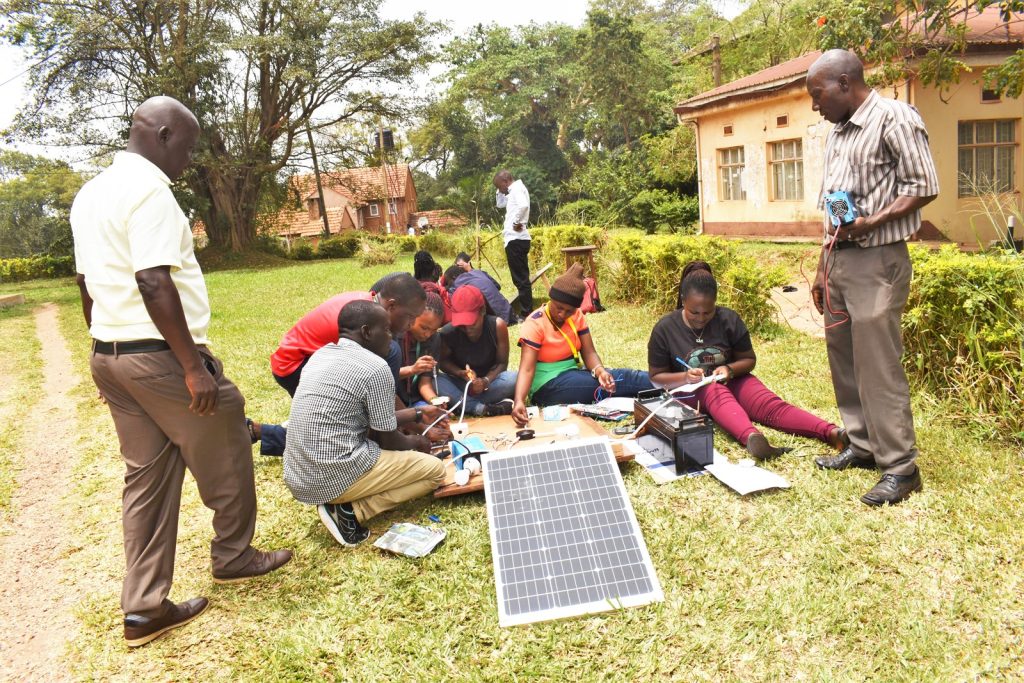 Dr. Denis Okello (L), Head, Department of Physics at Makerere University, and Mr. Musoke Michael, Technician in the same Department guiding the students through the process of solar installation. Department of Physics, Makerere University, Kampala Uganda, East Africa.