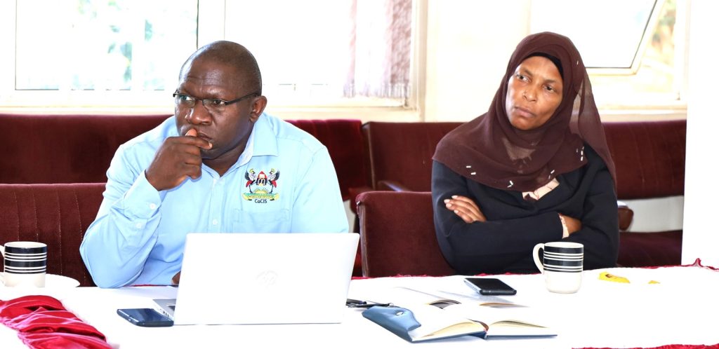 Dean SCIT Dr. Joseph Balikuddembe  and a staff member attending the meeting. Conference Hall, Level 4, Block A, College of Computing and Information Sciences (CoCIS), Makerere University, Kampala Uganda, East Africa.