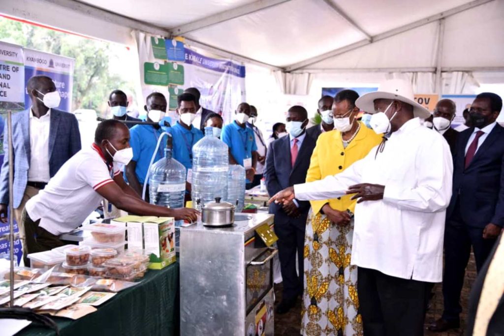 President Yoweri Museveni and First Lady Hon. Janet Museveni listen to Dr. Peter Tumutegyereize (Left) explain how the Mak Solar Cooker works. Photo: Courtesy/NCHE@20, Kololo Ceremonial Grounds. Kampala, Uganda, East Africa.
