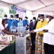 President Yoweri Museveni and First Lady Hon. Janet Museveni listen to Dr. Peter Tumutegyereize (Left) explain how the Mak Solar Cooker works. Photo: Courtesy/NCHE@20, Kololo Ceremonial Grounds. Kampala, Uganda, East Africa.