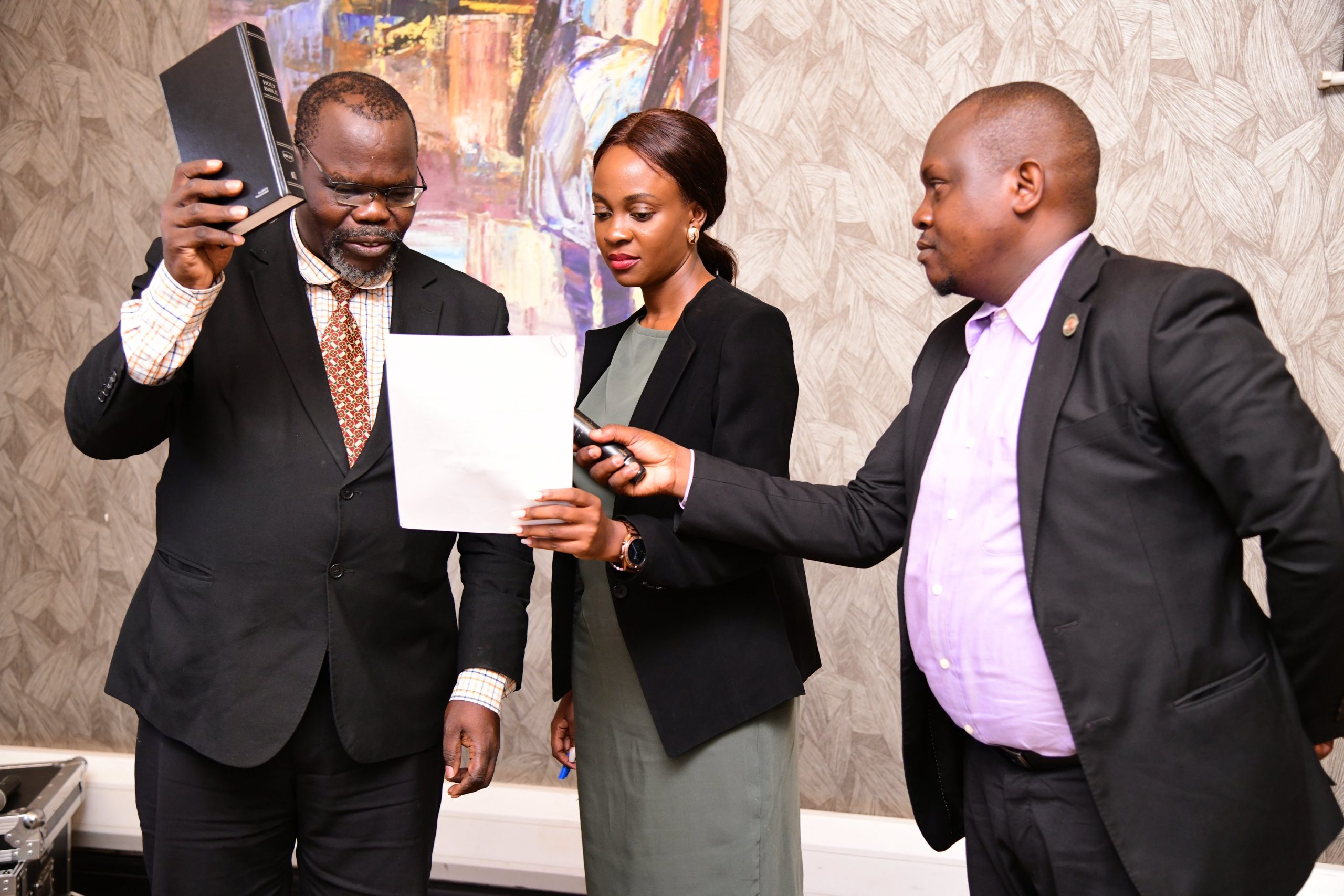 Her Worship Evelyn Najjuuko (Centre) assists the Chairperson of the Makerere University Staff Appeals Tribunal, Dr. Henry Onoria (Left) to take his oath on 16th November 2023. Right is Mr. Peter Eneru, Clerk to the Staff Appeals Tribunal. Makerere University Staff Appeals Tribunal Swearing-In Ceremony, 16th November 2023, Mestil Hotel, Kampala Uganda.