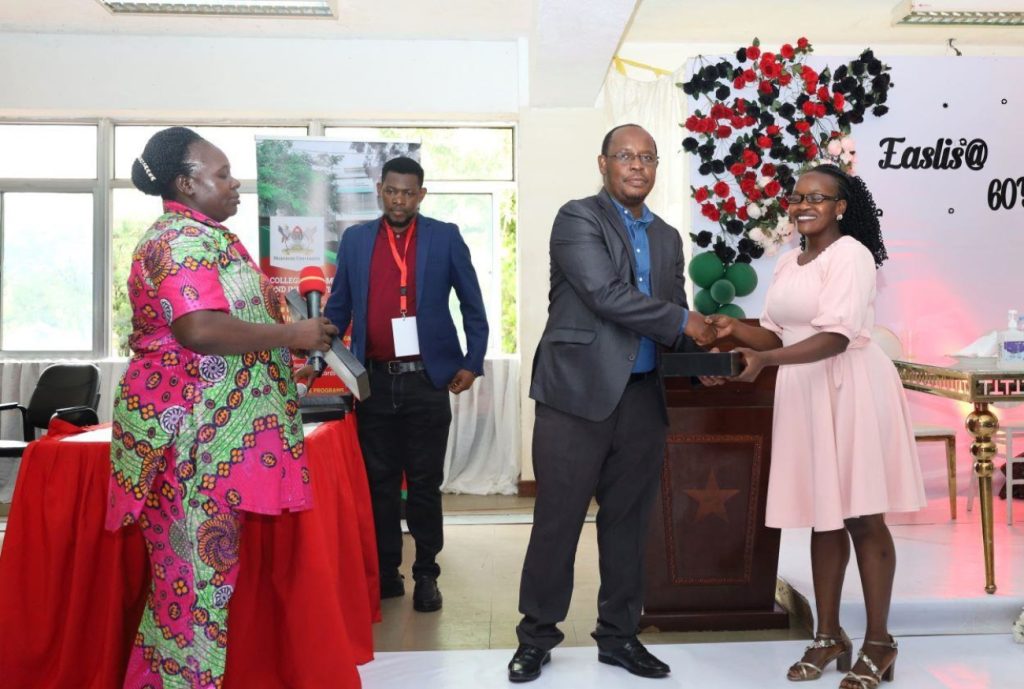 Aguttu (R) receiving a plaque on behalf of her father Mr. Boniface Odongo. EASLIS@60 Luncheon, 10th November 2023, Big Lab 2, Block B, College of Computing and Information Sciences (CoCIS), Makerere University, Kampala Uganda, East Africa.