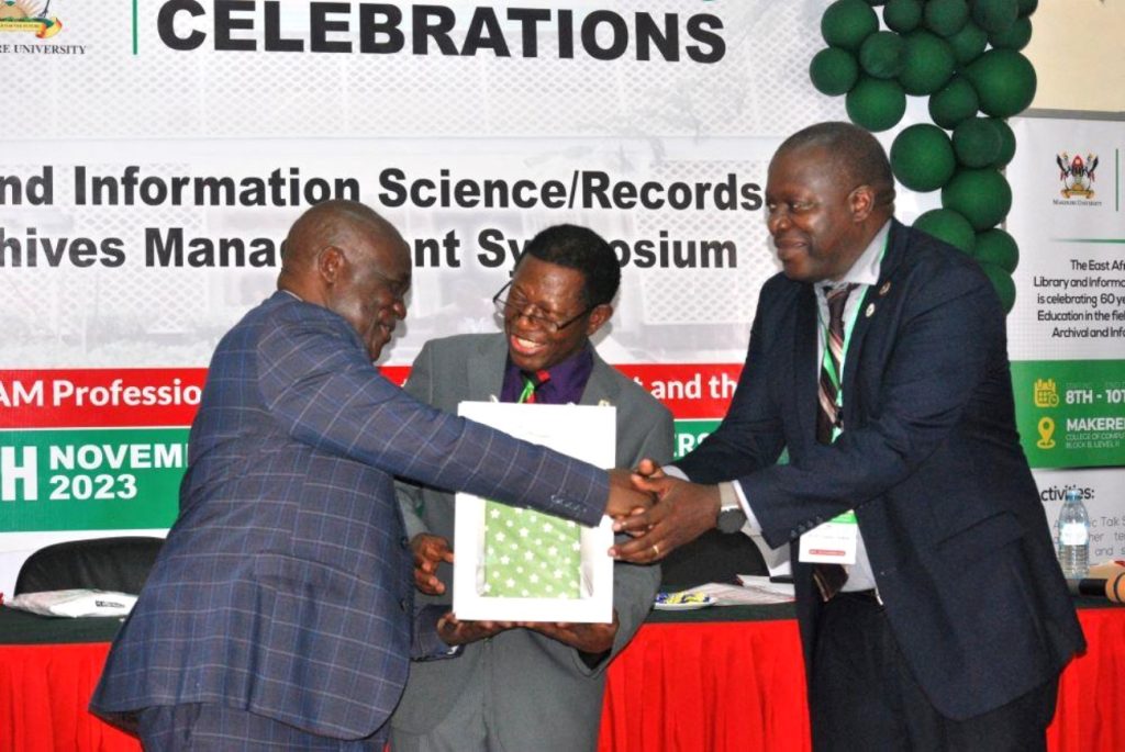 Hon. Muruli Mukasa (L) after receiving a gift from Prof. Buyinza Mukadasi (C) and Prof. Tonny Oyana (R). EASLIS@60 Conference, 8th-10th November 2023, Big Lab 2, Block B, College of Computing and Information Sciences (CoCIS), Makerere University, Kampala Uganda, East Africa.