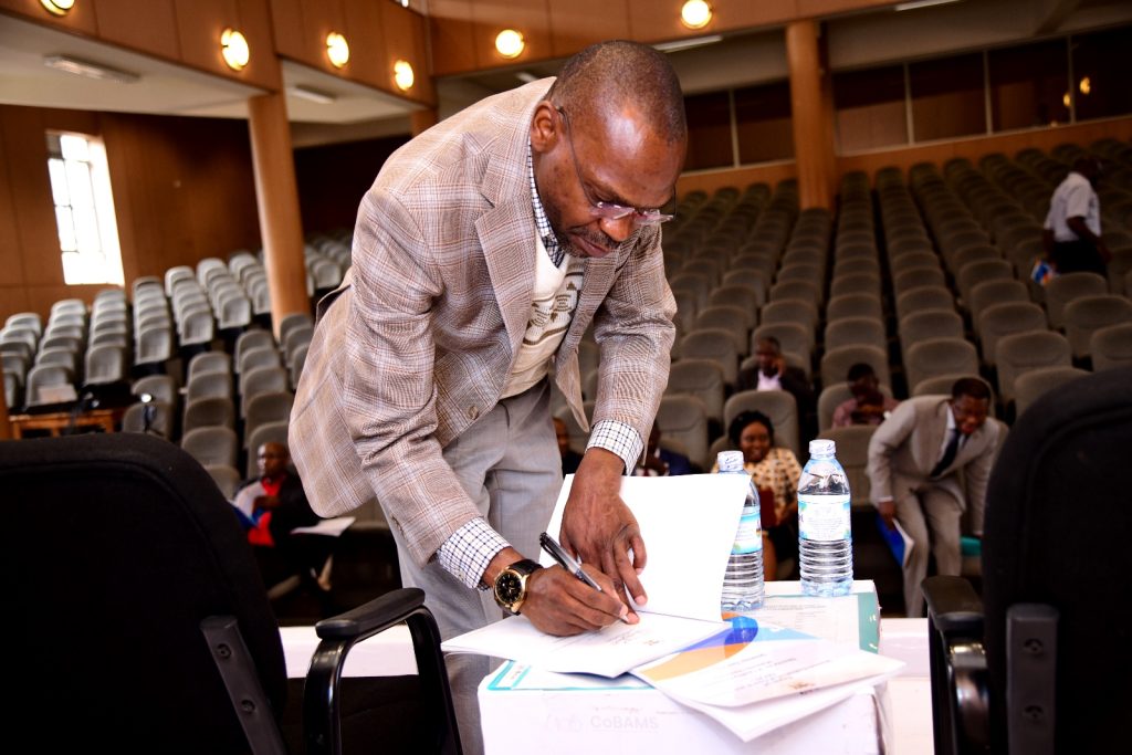 Prof. Umar Kakumba signs a copy of the report at the launch event. Launch of SECAT Report for Semester Two 2022/2023 by the Quality Assurance Director, 24th November 2023, Yusuf Lule Central Teaching Facility Auditorium, Makerere University, Kampala Uganda, East Africa.