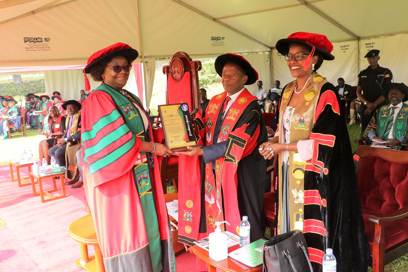 Hon. Dr. John Chrysestom Muyingo (Centre) who represented the Minister of Education and Sports Hon. Janet Museveni presents the Vice Chancellor's Research Excellence Award to Prof. Rhoda Wanyenze (Left) as the Chairperson of Council, Mrs. Lorna Magara (Right) witnesses on 29th January 2024. 74th Graduation Ceremony, Day 1, 29th January 2024, School of Public Health, College of Health Sciences (CHS), Freedom Square, Makerere University, Kampala Uganda, East Africa.