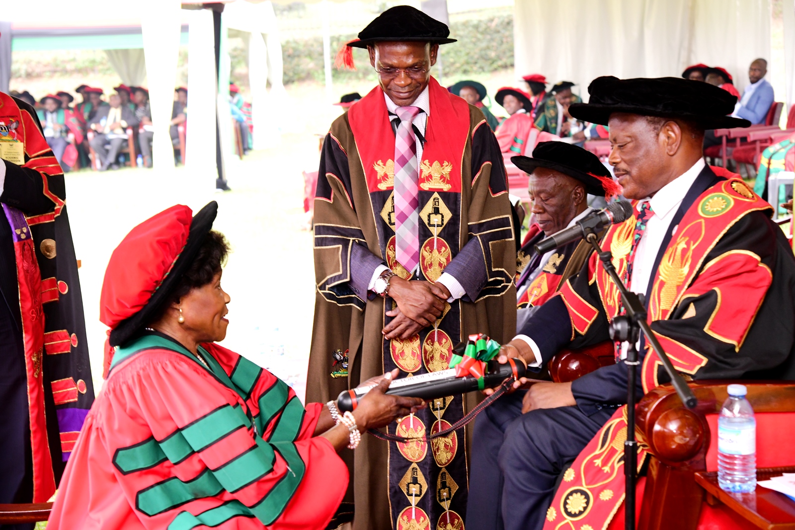 The Vice Chancellor, Prof. Barnabas Nawangwe (Right) presents Hon. Betty Oyella Bigombe (Left) with the Honorary Doctor of Laws, Honoris Causa of Makerere University as the Deputy Vice Chancellor (Academic Affairs), Prof. Umar Kakumba (2nd Left) witnesses on Day 1 of the 74th Graduation Ceremony on 29th January 2024. 74th Graduation Ceremony, Day 1, 29th January 2024, Freedom Square, Makerere University, Kampala Uganda, East Africa.