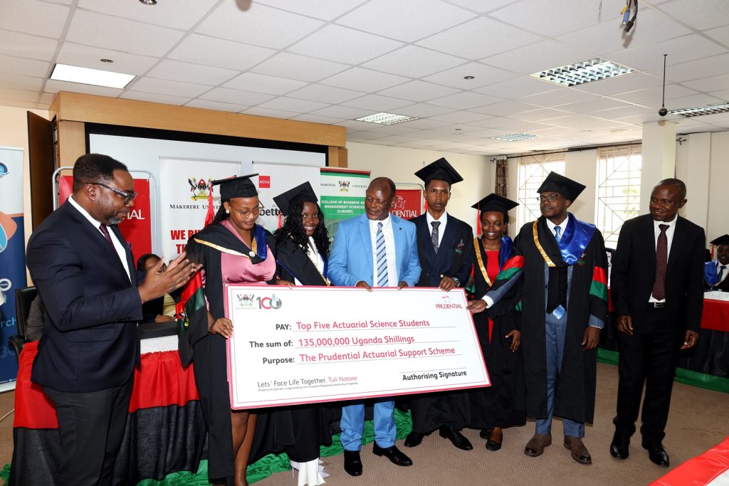Prof. Barnabas Nawangwe, Prof. Eria Hisali and Mr Tetteh Ayitevie join the top five Actuarial Science students as they pose with a dummy cheque of UGX 135 million from the Prudential Actuarial Support Scheme (PASS) towards scholarships fully covering their professional exam fees. Prudential Assurance, ACCA Uganda and EPRC award ceremony for best performing business graduates, 12th March 2024, Conference Room, Room 2.2B, Level 2, School of Business, College of Business and Management Sciences (CoBAMS), Makerere University, Kampala Uganda, East Africa.