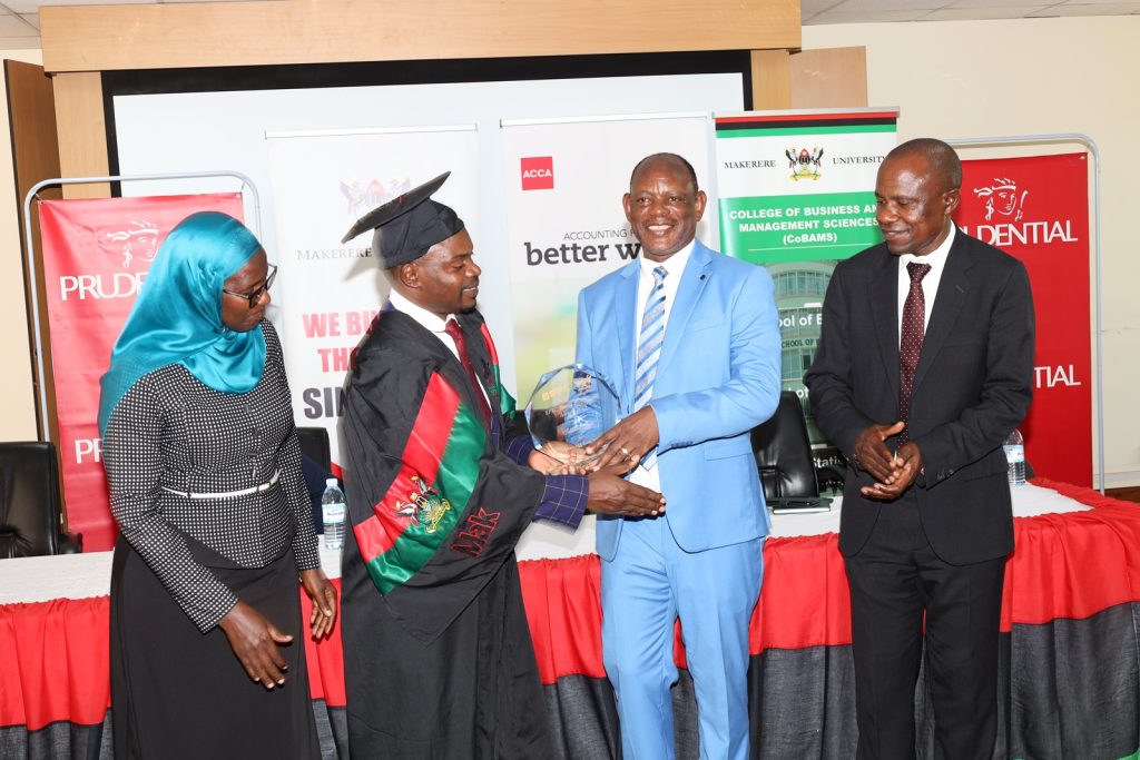 Prof. Barnabas Nawangwe presents the EPRC Award to Mr. Sebuliba Jude as Prof. Eria Hisali and Ms. Fatumah Namubiru witness. Prudential Assurance, ACCA Uganda and EPRC award ceremony for best performing business graduates, 12th March 2024, Conference Room, Room 2.2B, Level 2, School of Business, College of Business and Management Sciences (CoBAMS), Makerere University, Kampala Uganda, East Africa.