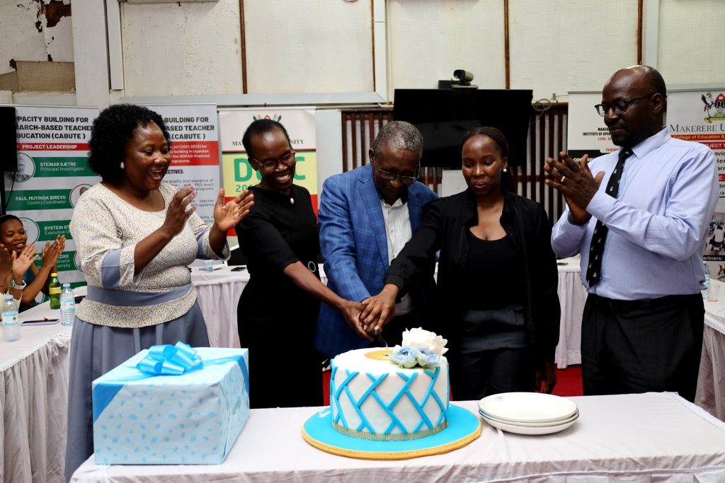 Cake cutting by Dr. Samuel Siminyu and members of his family as Dr. Harriet Nabushawo (Left) and Prof. Paul Birevu Muyinda (Right) applaud. Dr. Samuel Ndeda Siminyu farewell luncheon by the Institute of Open, Distance and e-Learning (IODeL) on 27th March 2024, AVU Conference Room, College of Education and External Studies (CEES), Makerere University, Kampala Uganda, East Africa.