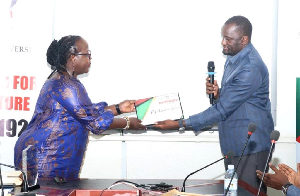 Prof. Ahikire receives a certificate of recognition from the US representative Simon Kizito. Prof. Josephine Ahikire Hands Over College of Humanities and Social Sciences (CHUSS) Leadership to Assoc. Prof. Helen Nambalirwa Nkabala, 31st May 2024, CHUSS Smart room, Makerere University, Kampala Uganda, East Africa.