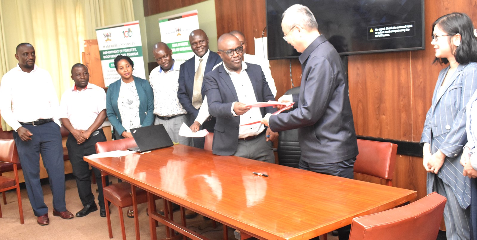 The representative of Makerere University Vice Chancellor, also Dean SFEGS, Dr Revocatus Twinomuhangi handing over signed MoU to the Vice President of NUIST. Makerere University-Nanjing University of Information Science and Technology (NUIST) MoU Signing to formalize collaboration in teaching and learning, research and publication, technology transfer, and resource mobilization, 12th July 2024, School of Forestry, Environmental, and Geographical Sciences (SFEGS) Board Room, College of Agricultural and Environmental Sciences (CAES), Kampala Uganda, East Africa.