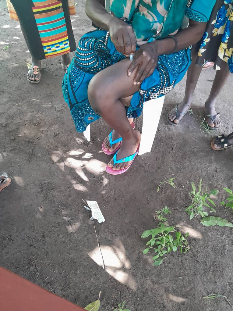 A woman self-injecting while demonstrating to fellow women in Oyam district. Makerere University School of Public Health (MakSPH) Innovations for Choice and Autonomy (ICAN) project study I-CAN/Nsobola/An atwero social support intervention, piloted in Mayuge and Oyam districts in 2023, Dissemination on July 31, 2024 at Golden Tulip Hotel, Kampala Uganda, East Africa.