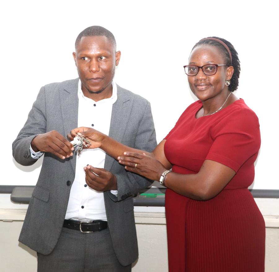 Ms. Joseline Biganja (R) handing over the office keys to Mr. Micheal Mbaine. Handover of the College of Humanities and Social Sciences (CHUSS) Bursar Office from Ms. Joseline Biganja to Mr. Michael Mbaine, 6th August 2024, CHUSS Smart Room, Makerere University, Kampala Uganda, East Africa.