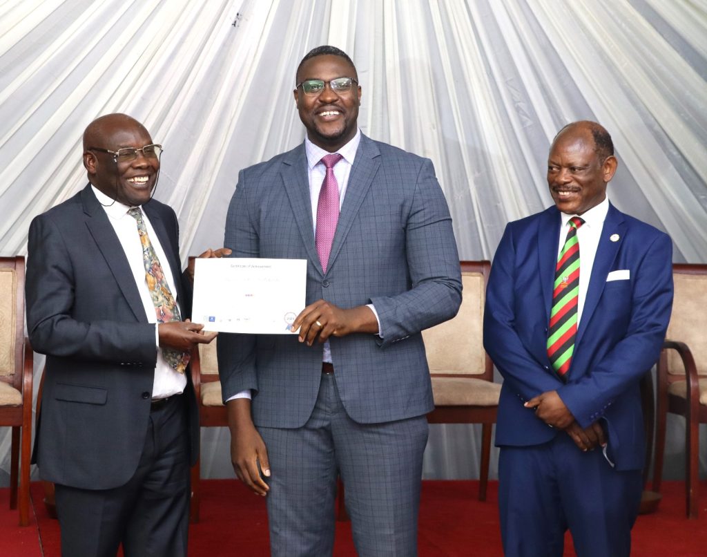 A graduating IGE fellow receiving a certificate from Hon. Okaasai Opolot witnessed by Prof. Nawangwe. EfD Uganda, Makerere University, Kampala Uganda, East Africa graduation of Third Cohort of the Inclusive Green Economy (IGE) Capacity Building Program Fellows, 7th August 2024, Kampala Sheraton Hotel.